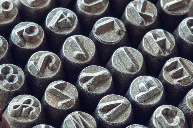Close-up of individual metal hand stamp letter dies showing engraved character faces